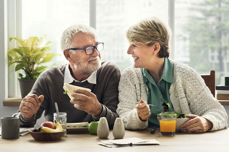 an elderly couple enjoying their meal thanks to dental implants